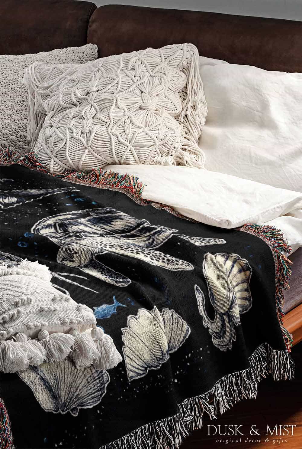 Woven cotton blanket featuring detailed marine life illustration — orca, dolphins, sea turtle, octopus, jellyfish, seashells, and fish on a black background.