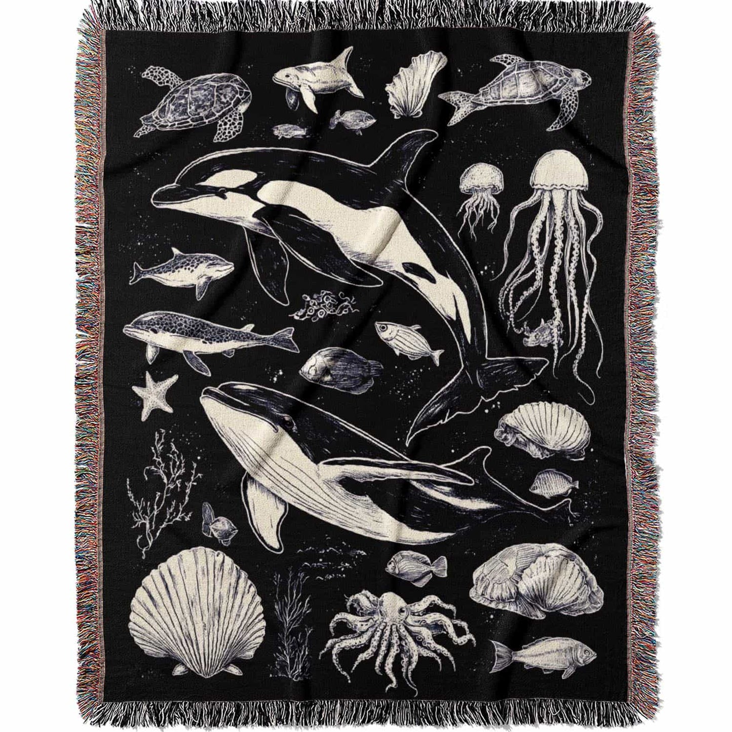 Woven cotton blanket featuring detailed ocean life illustration — whales, orca, turtles, jellyfish, octopus, seashells, fish, and coral on a black background.