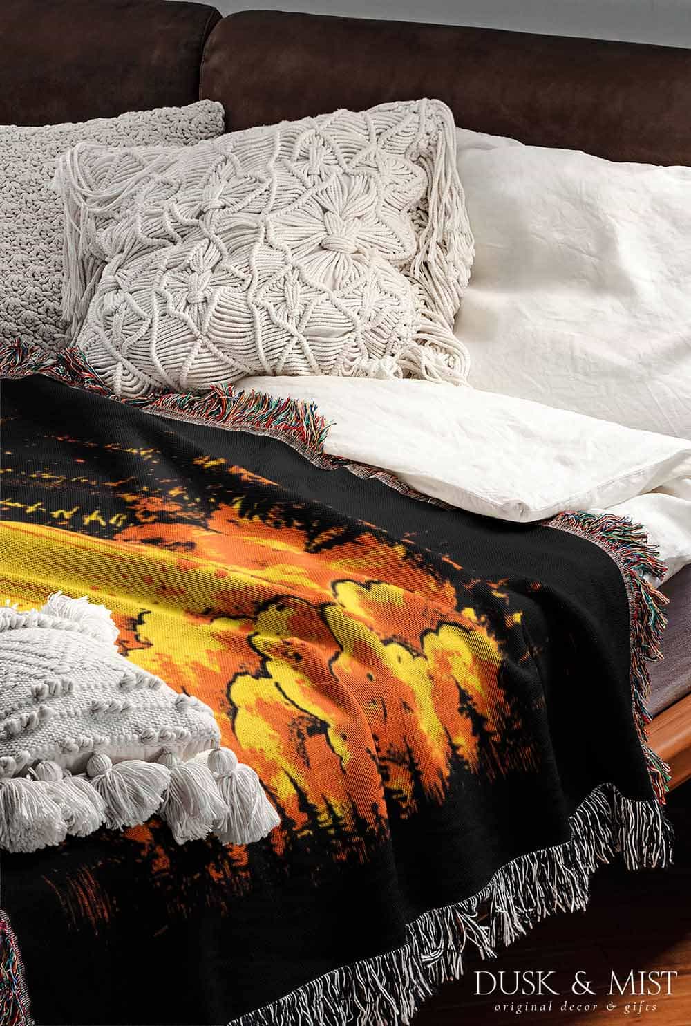 Woven cotton blanket featuring a UFO with a fiery orange beam illuminating a dark forest, with glowing clouds and night sky details.