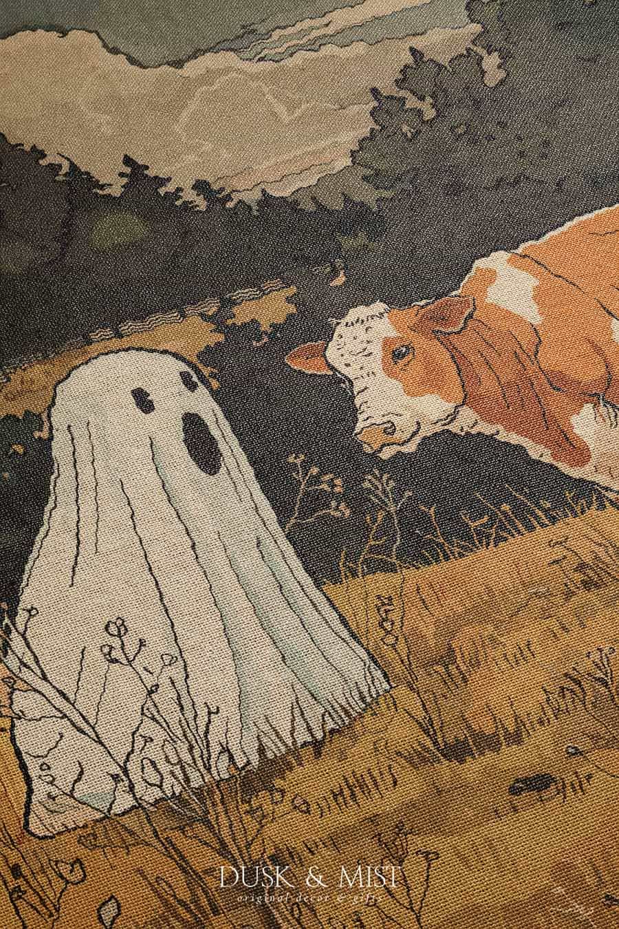 Woven cotton blanket featuring a small ghost standing in a golden meadow facing a brown and white cow, with a rustic cabin and forested hills in the background.