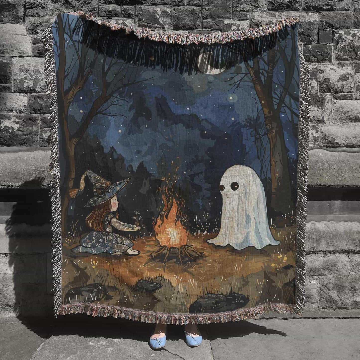 Woven cotton blanket featuring a witch and a ghost sitting by a campfire under a crescent moon in a dark forest setting.