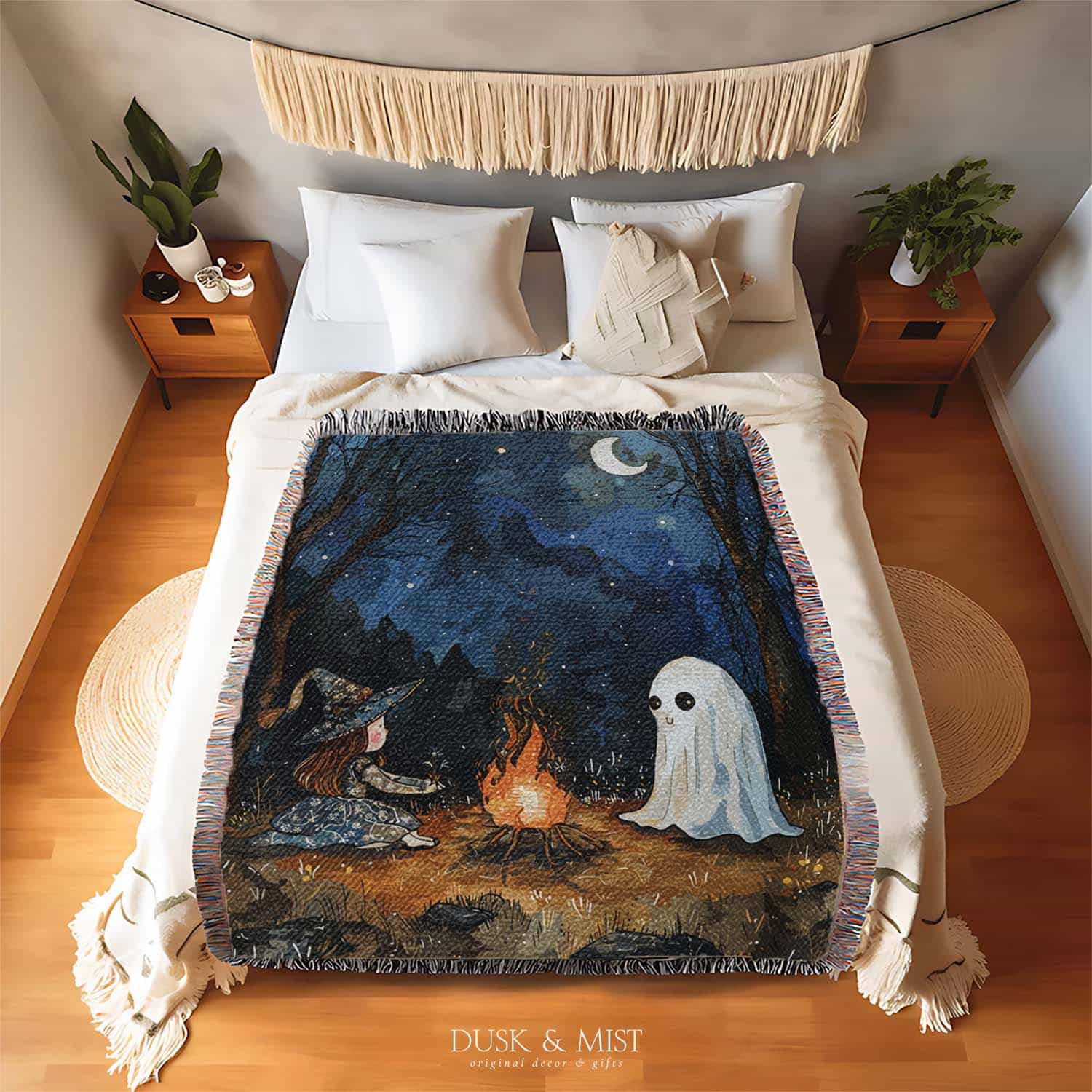 Woven cotton blanket featuring a witch and a ghost sitting by a campfire under a crescent moon in a dark forest setting.