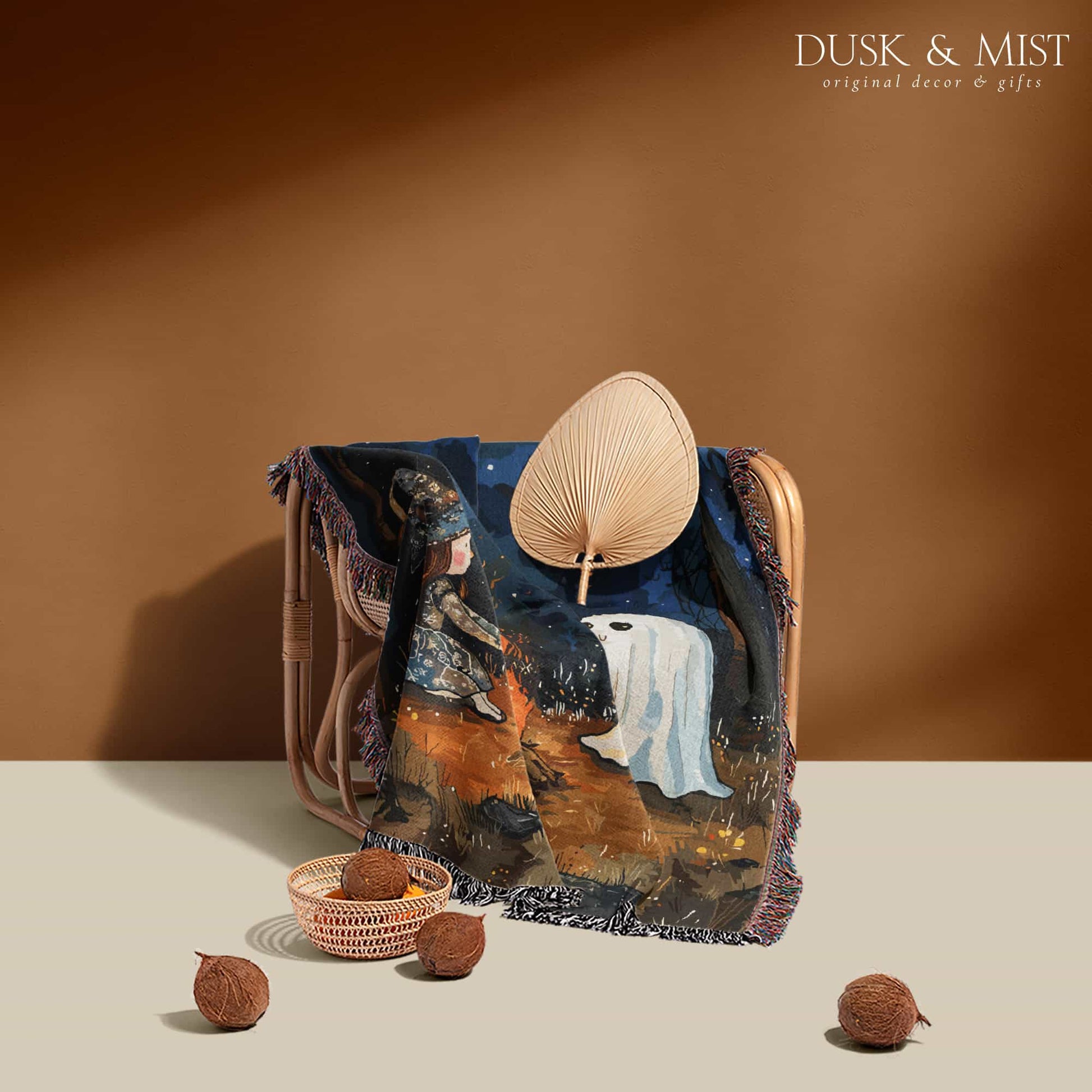 Woven cotton blanket featuring a witch and a ghost sitting by a campfire under a crescent moon in a dark forest setting.