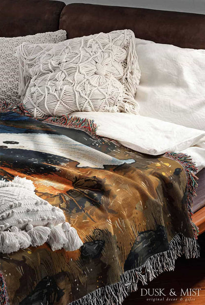 Woven cotton blanket featuring a witch and a ghost sitting by a campfire under a crescent moon in a dark forest setting.