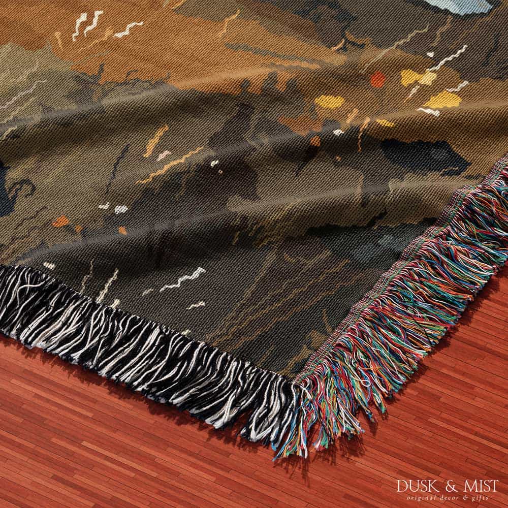 Woven cotton blanket featuring a witch and a ghost sitting by a campfire under a crescent moon in a dark forest setting.