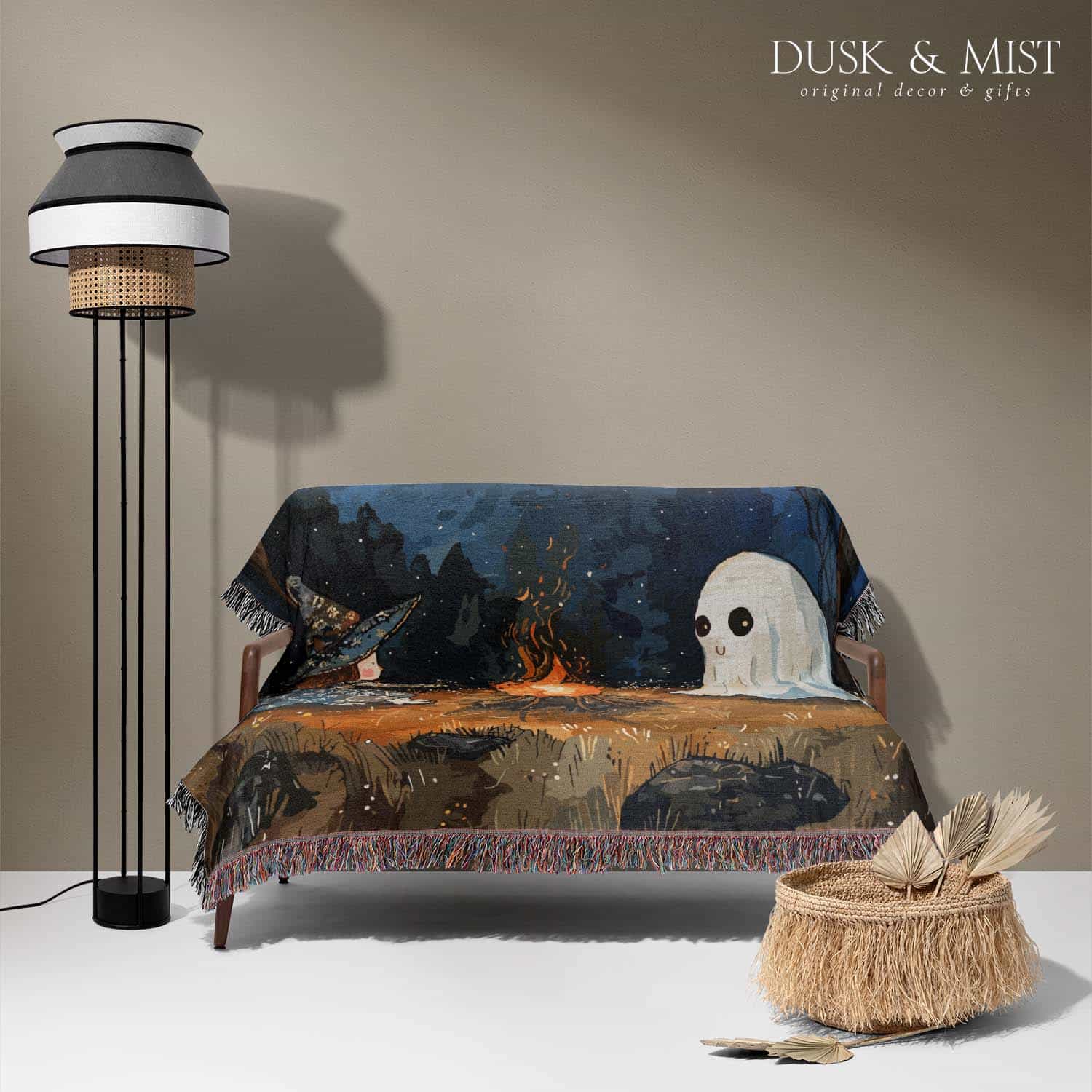 Woven cotton blanket featuring a witch and a ghost sitting by a campfire under a crescent moon in a dark forest setting.