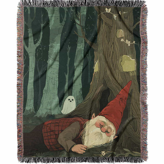 Woven cotton blanket depicting a sleeping gnome under a large tree, with a small ghost-like forest spirit in the background surrounded by dark green woods.