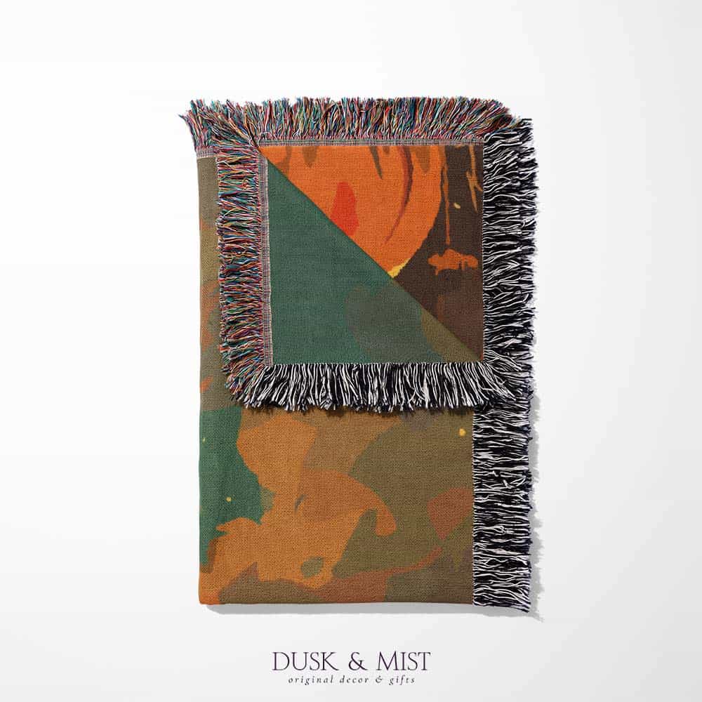 Woven cotton blanket depicting a ghost carrying a basket in a pumpkin-filled autumn field under a twilight sky.  