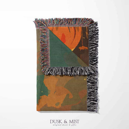 Woven cotton blanket depicting a ghost carrying a basket in a pumpkin-filled autumn field under a twilight sky.  