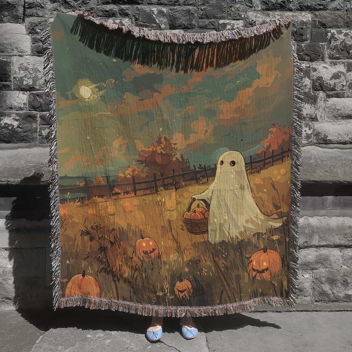 Woven cotton blanket depicting a ghost carrying a basket in a pumpkin-filled autumn field under a twilight sky.  