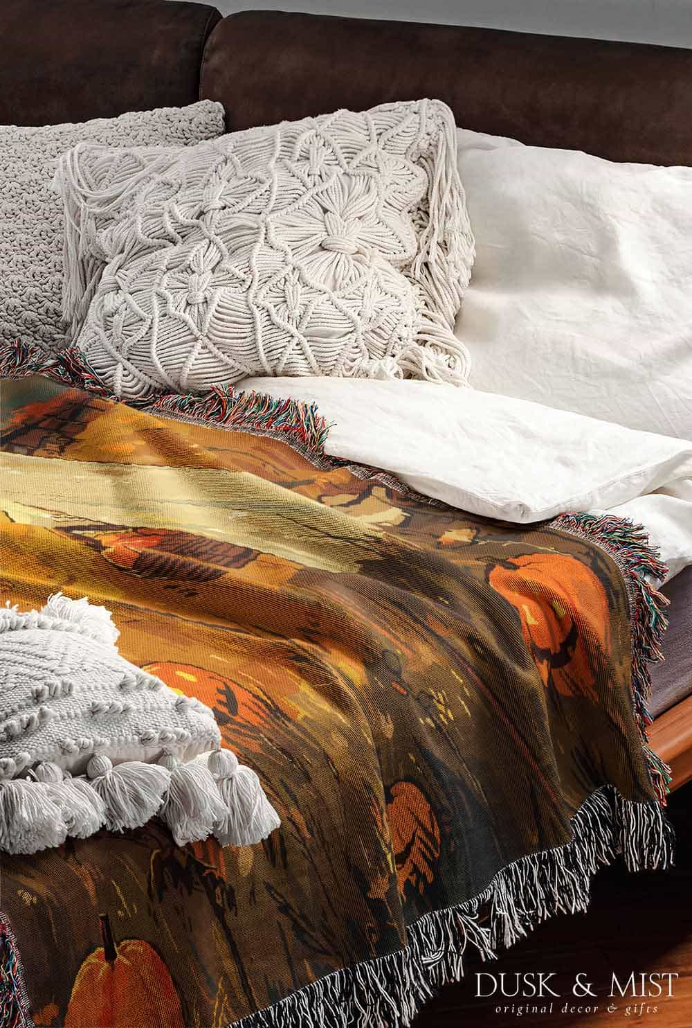 Woven cotton blanket depicting a ghost carrying a basket in a pumpkin-filled autumn field under a twilight sky.  