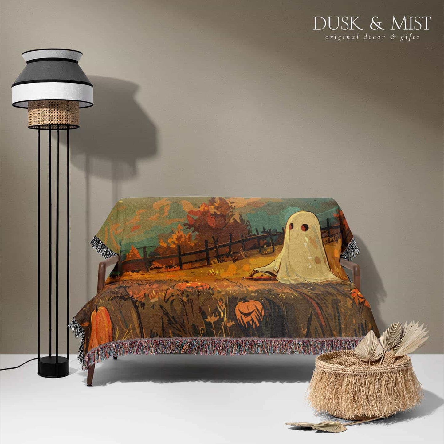 Woven cotton blanket depicting a ghost carrying a basket in a pumpkin-filled autumn field under a twilight sky.  