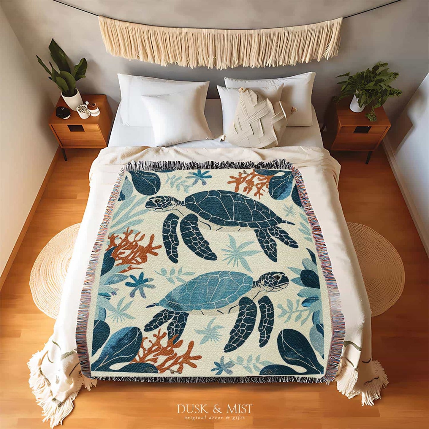 Woven cotton blanket featuring two sea turtles swimming among coral and aquatic plants, designed in teal, orange, and cream tones.  