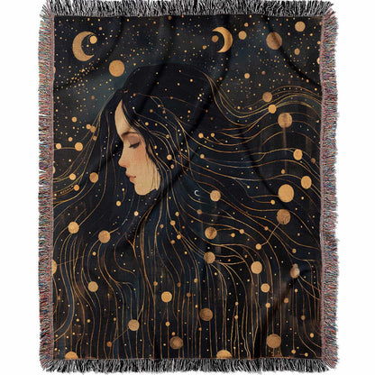 Woven cotton blanket featuring a profile of a woman with flowing hair illustrated as starry constellations, accented with golden moons and celestial motifs on a dark background.