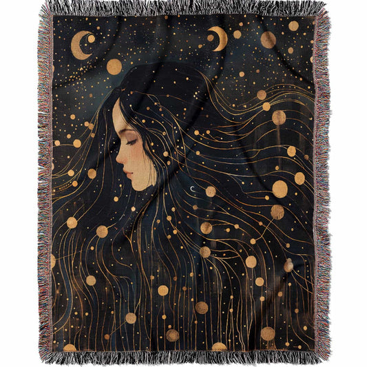 Woven cotton blanket featuring a profile of a woman with flowing hair illustrated as starry constellations, accented with golden moons and celestial motifs on a dark background.