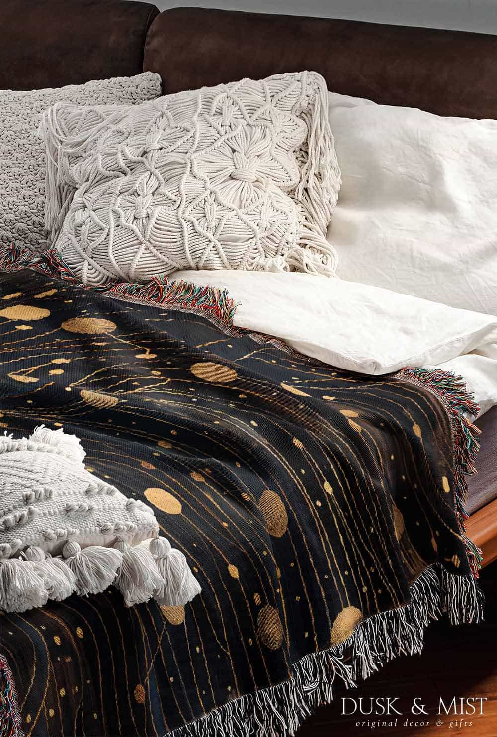 Woven cotton blanket featuring a profile of a woman with flowing hair illustrated as starry constellations, accented with golden moons and celestial motifs on a dark background.