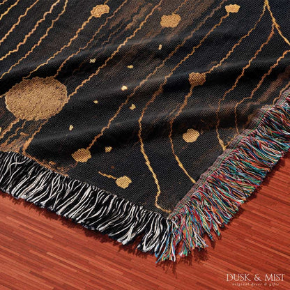 Woven cotton blanket featuring a profile of a woman with flowing hair illustrated as starry constellations, accented with golden moons and celestial motifs on a dark background.