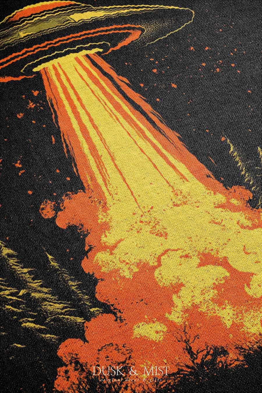 Woven cotton blanket featuring a UFO with a fiery orange beam blasting into a forest, with smoke clouds and a small human silhouette running at the bottom.