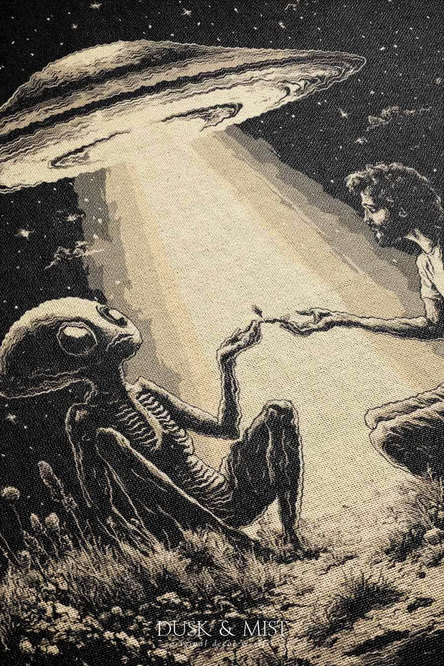 Woven cotton blanket featuring an alien and a human seated under a UFO’s glowing beam, reaching hands toward each other against a starry night sky.
