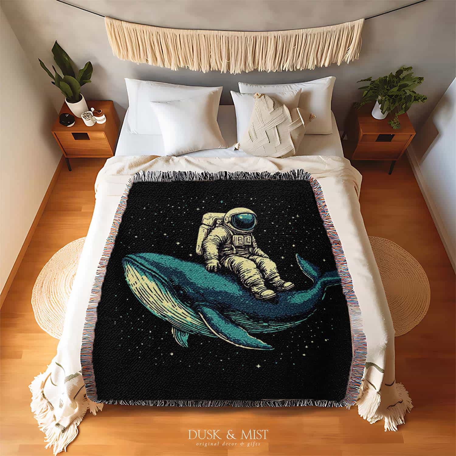 Woven cotton blanket featuring an astronaut riding a whale through space with colorful stars on a black background.