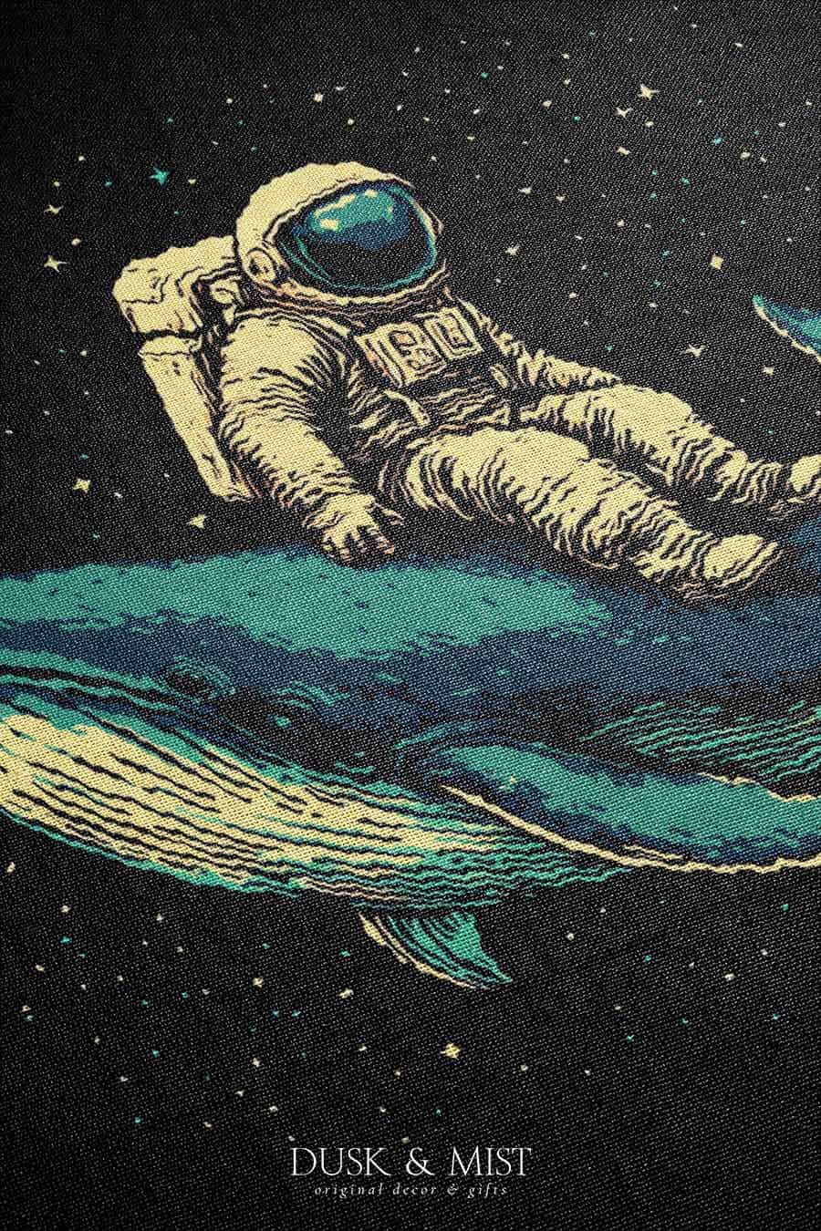 Woven cotton blanket featuring an astronaut riding a whale through space with colorful stars on a black background.