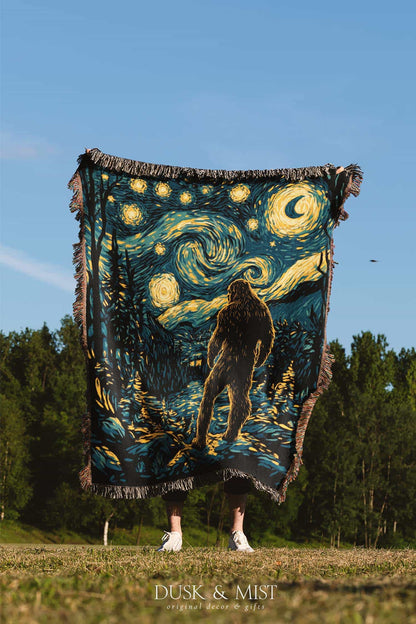 Woven cotton blanket featuring Bigfoot in a forest beneath a Van Gogh-style starry night sky with swirling constellations and moonlight.