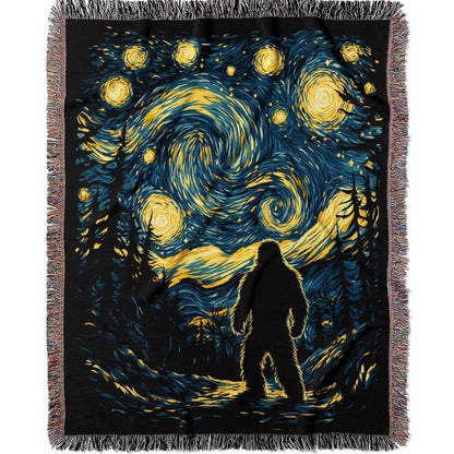 Woven cotton blanket featuring Bigfoot in silhouette against a Van Gogh-style starry night sky with swirling golden stars and dark forest trees.