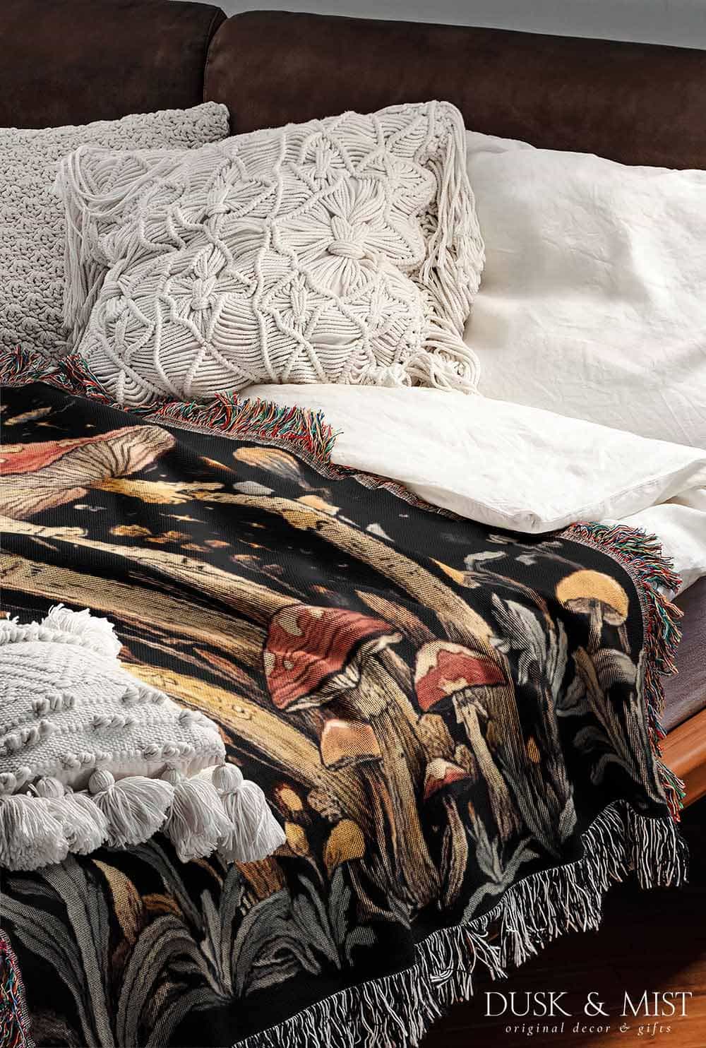 Woven cotton blanket featuring tall red-capped mushrooms under a starry sky with golden stars and surrounding plants on a black background.