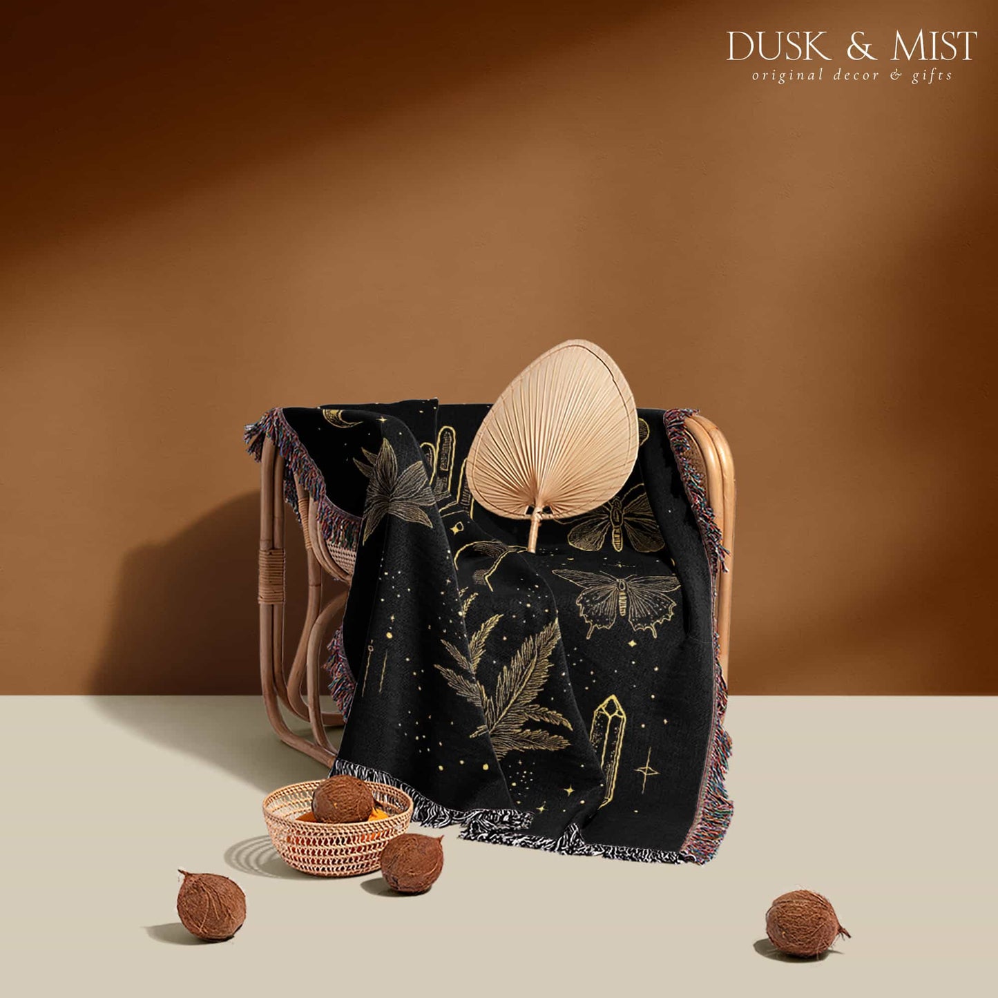 Woven cotton blanket with golden occult illustrations — palmistry hand, crescent moon, moth, snake, crystals, plants, and celestial symbols on a black background.