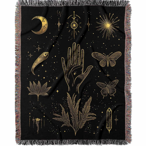 Woven cotton blanket with golden occult illustrations — palmistry hand, crescent moon, moth, snake, crystals, plants, and celestial symbols on a black background.