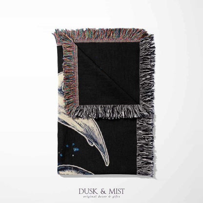Woven cotton blanket featuring detailed marine life illustration — orca, dolphins, sea turtle, octopus, jellyfish, seashells, and fish on a black background.