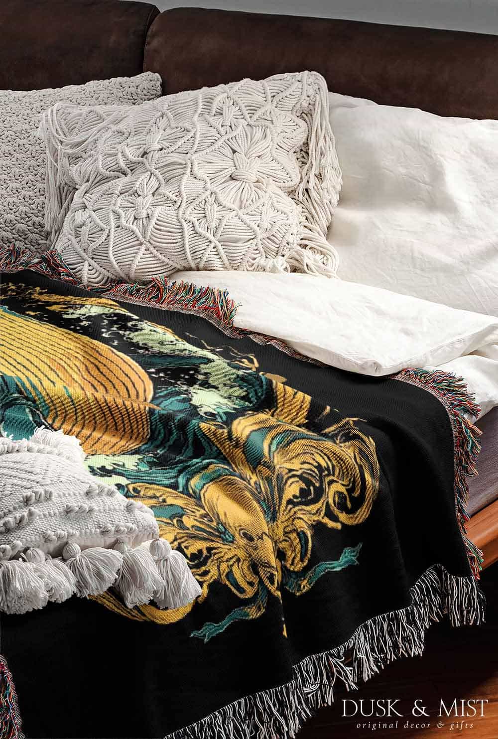 Woven cotton blanket featuring a warrior mermaid with flowing hair riding a whale, holding a spear, surrounded by ornate golden oceanic patterns.