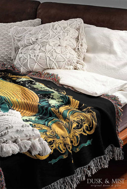 Woven cotton blanket featuring a warrior mermaid with flowing hair riding a whale, holding a spear, surrounded by ornate golden oceanic patterns.