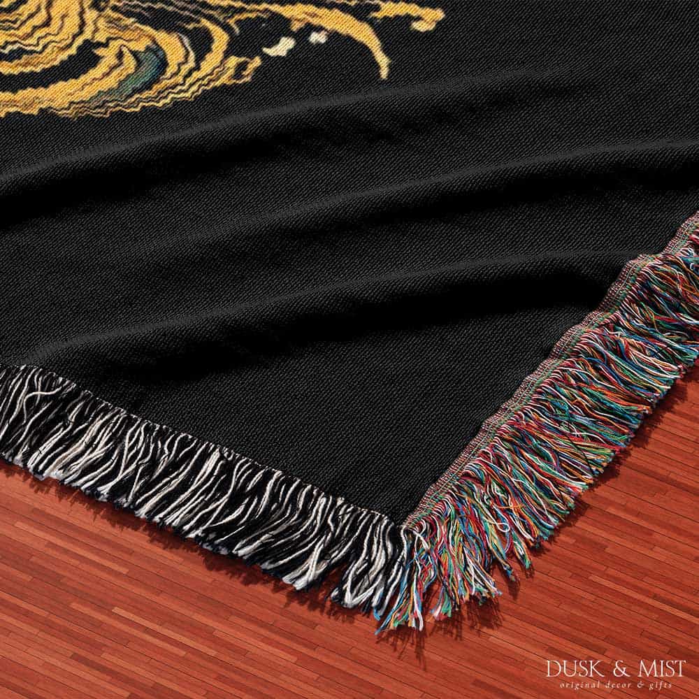 Woven cotton blanket featuring a warrior mermaid with flowing hair riding a whale, holding a spear, surrounded by ornate golden oceanic patterns.