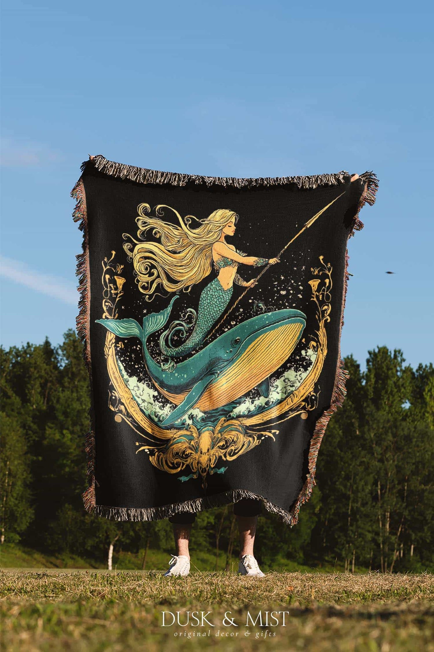 Woven cotton blanket featuring a warrior mermaid with flowing hair riding a whale, holding a spear, surrounded by ornate golden oceanic patterns.