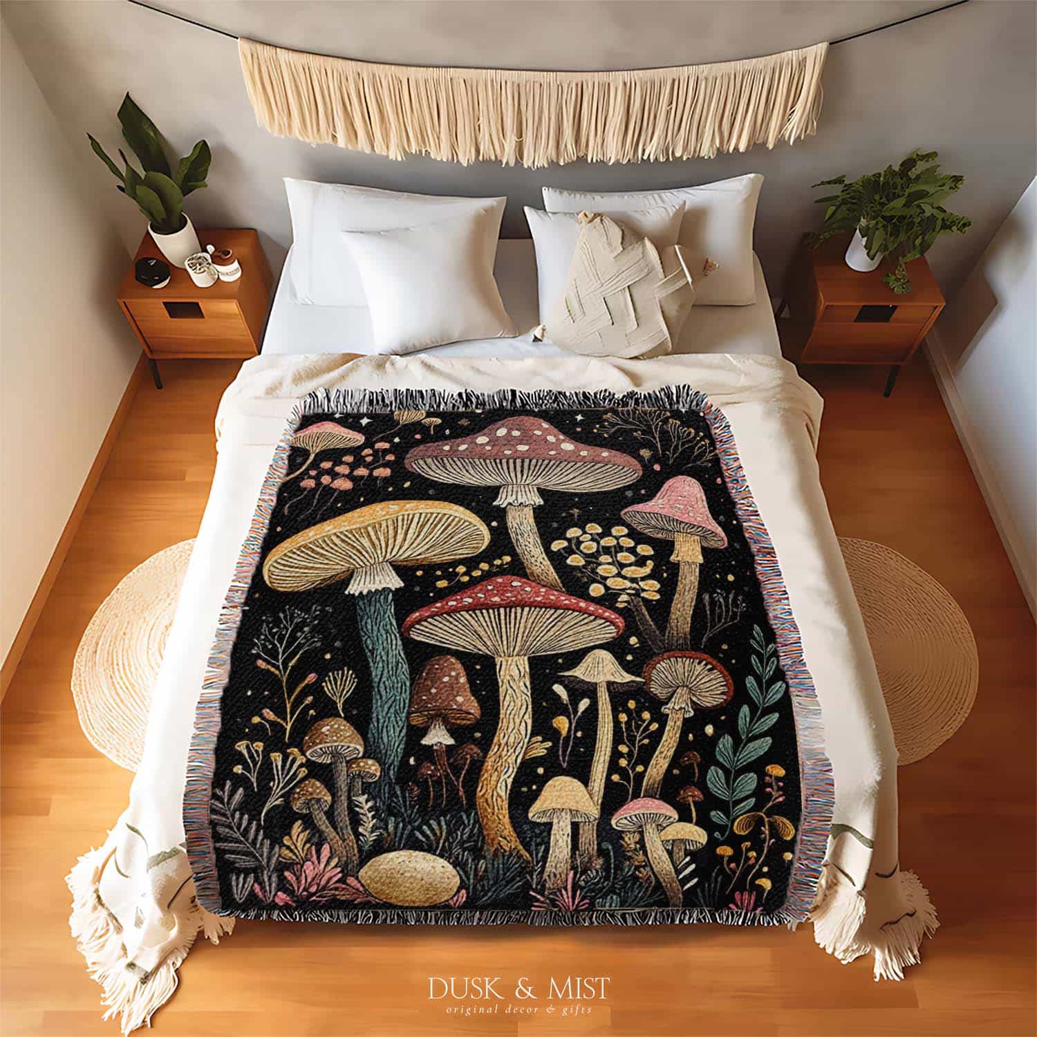 Woven cotton blanket featuring a botanical-style field of mushrooms in red, gold, and cream tones with surrounding plants and foliage on a black background.