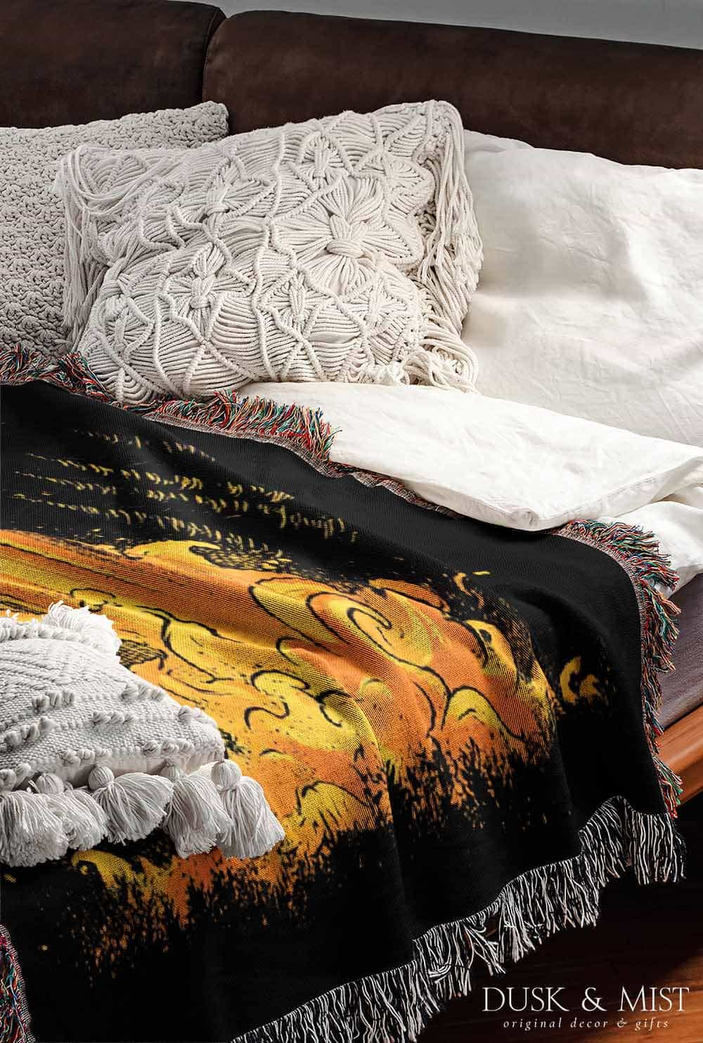Woven cotton blanket featuring a UFO casting a golden beam into the forest at night, with glowing clouds and cosmic light effects.