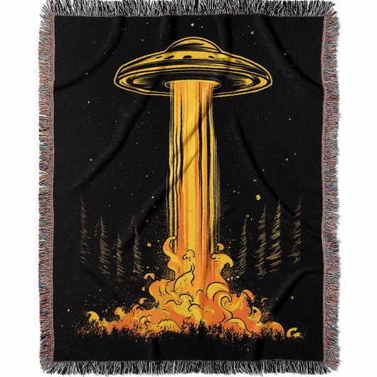 Woven cotton blanket featuring a UFO casting a golden beam into the forest at night, with glowing clouds and cosmic light effects.