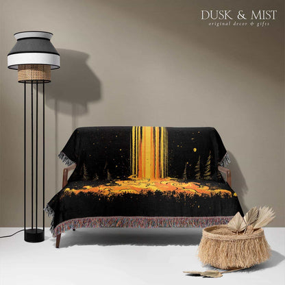 Woven cotton blanket featuring a UFO casting a golden beam into the forest at night, with glowing clouds and cosmic light effects.