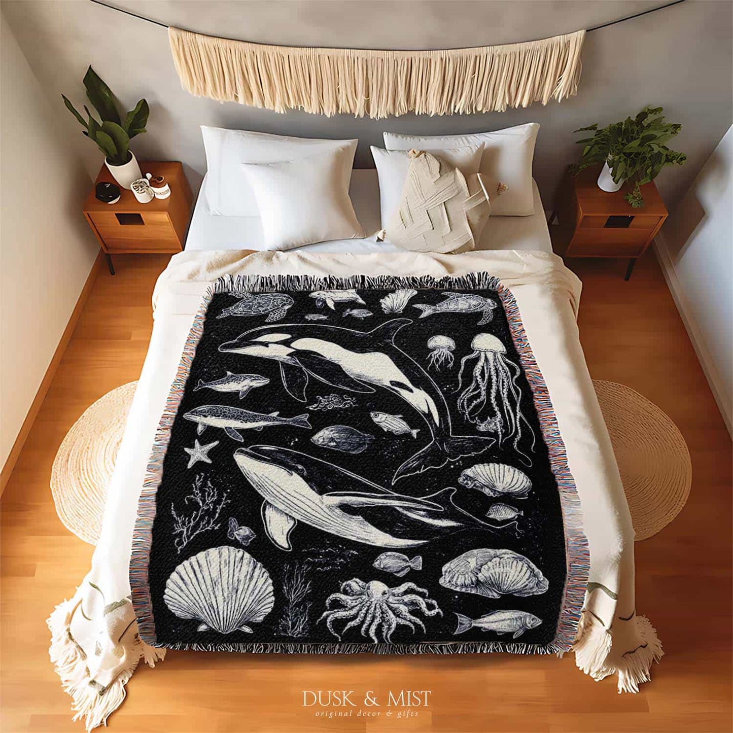 Woven cotton blanket featuring detailed ocean life illustration — whales, orca, turtles, jellyfish, octopus, seashells, fish, and coral on a black background.