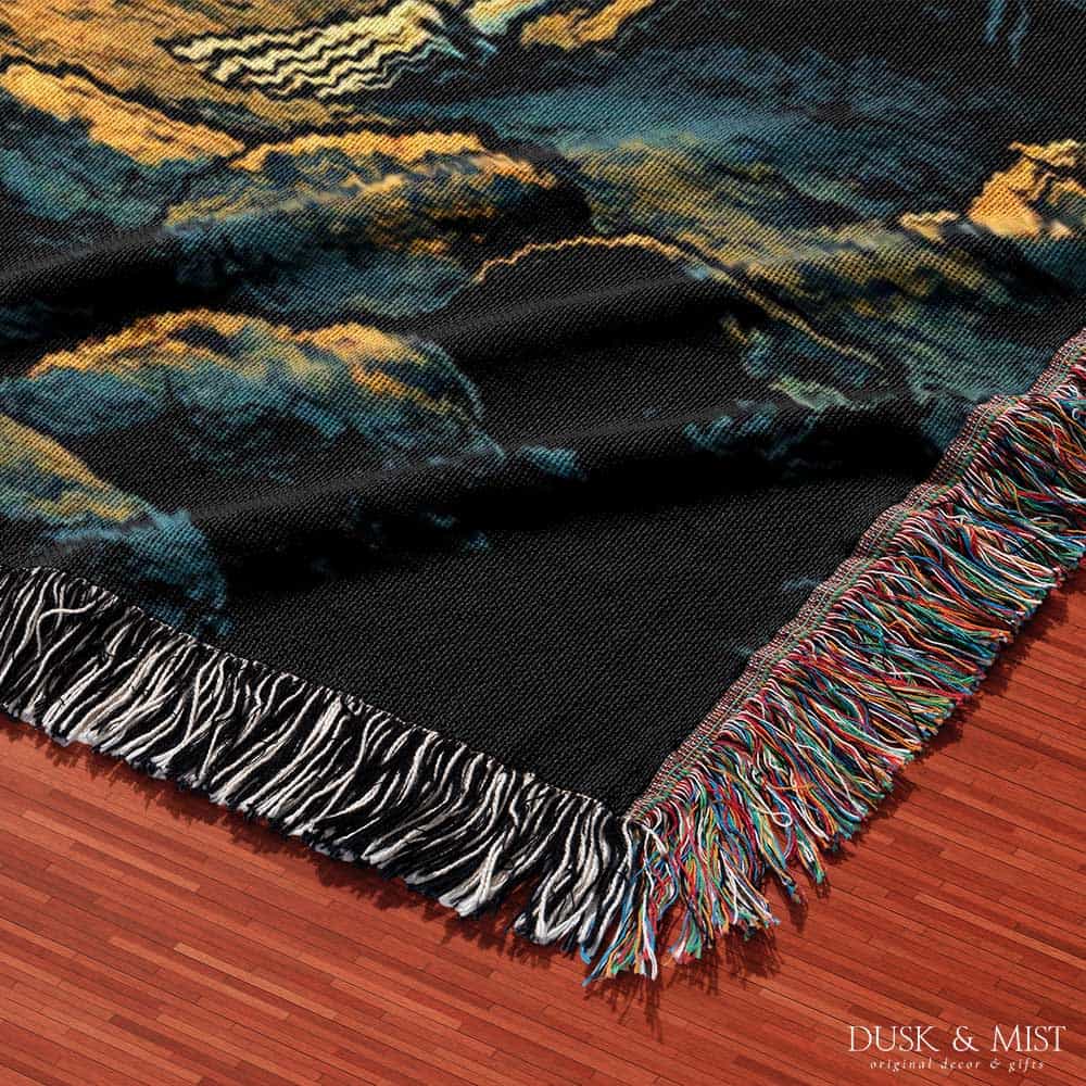 Woven cotton blanket showing two skeletons sitting around a campfire with a bear, log cabin, and full moon in a forest night scene.