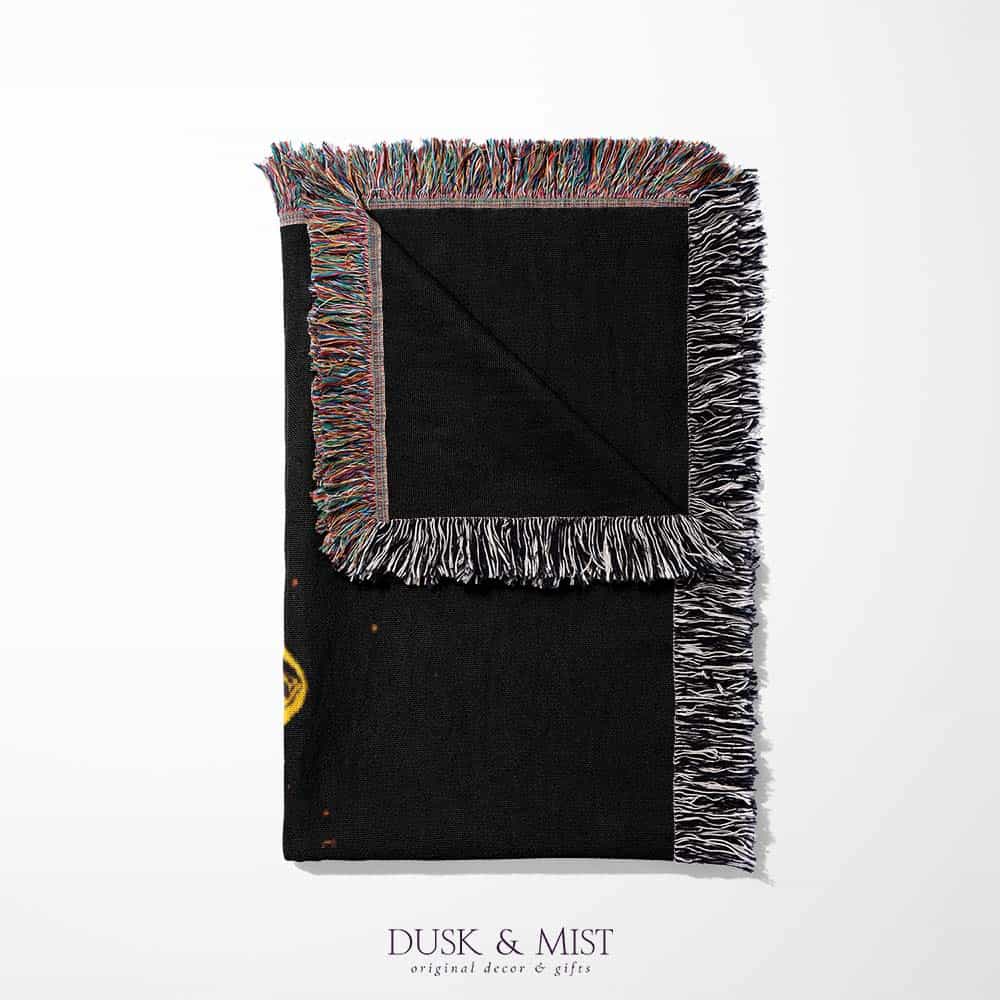 Woven cotton blanket featuring a UFO with a fiery orange beam illuminating a dark forest, with glowing clouds and night sky details.