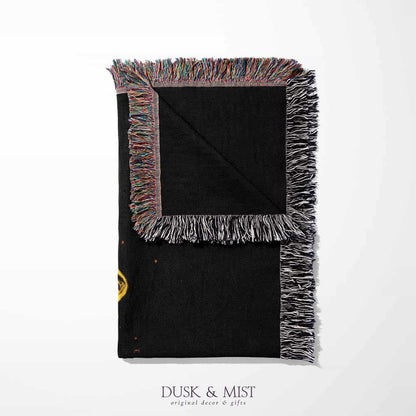 Woven cotton blanket featuring a UFO with a fiery orange beam illuminating a dark forest, with glowing clouds and night sky details.