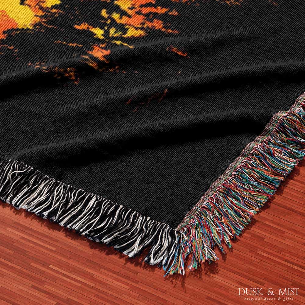 Woven cotton blanket featuring a UFO with a fiery orange beam illuminating a dark forest, with glowing clouds and night sky details.