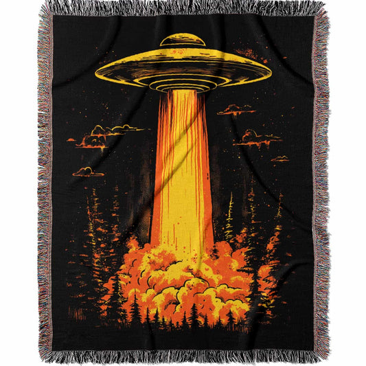 Woven cotton blanket featuring a UFO with a fiery orange beam illuminating a dark forest, with glowing clouds and night sky details.