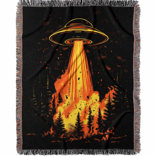 Woven cotton blanket featuring a UFO with a fiery orange beam blasting into a dark forest, with glowing explosions and cosmic night details.