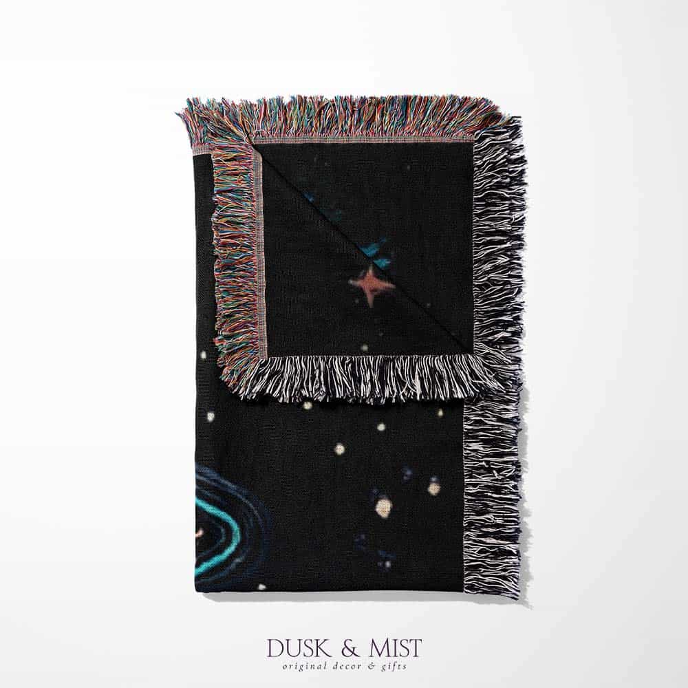 Blanket with a UFO abduction of a cow design against a starry night sky.